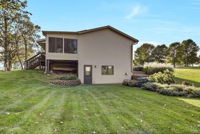 rear view of property featuring a lawn and a sunroom