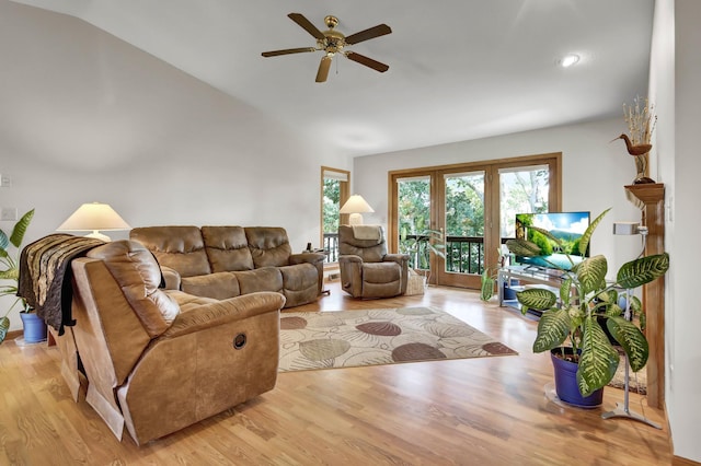 living room featuring ceiling fan, light wood-type flooring, and vaulted ceiling