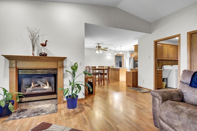 living room with light wood-type flooring, vaulted ceiling, ceiling fan, and washer and clothes dryer