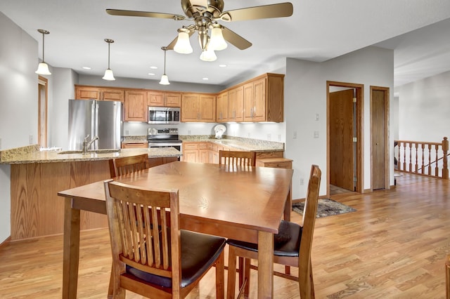 dining space featuring ceiling fan, sink, and light hardwood / wood-style floors