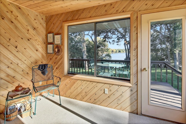 doorway to outside with wooden walls, a water view, plenty of natural light, and wooden ceiling