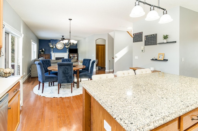 kitchen featuring open floor plan, a center island, decorative light fixtures, light wood-type flooring, and a fireplace