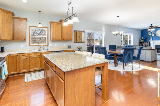 kitchen featuring a sink, decorative light fixtures, open floor plan, a breakfast bar area, and light wood finished floors