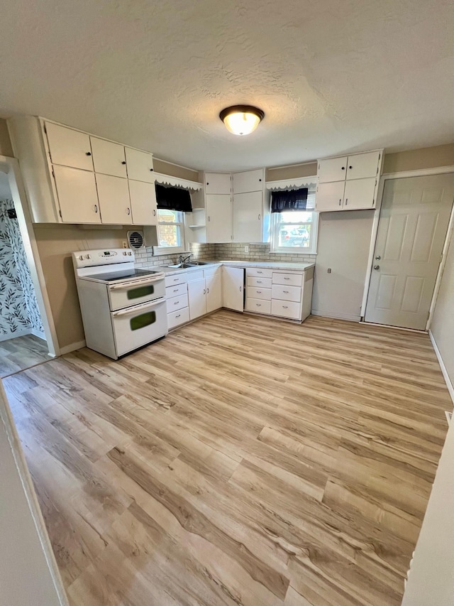 511 Division St N, Clara City, MN 56222 - kitchen with light wood-type flooring, range with two ovens, white cabinets, and a healthy amount of sunlight