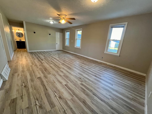 511 Division St N, Clara City, MN 56222 - unfurnished living room with light wood-style flooring, visible vents, a ceiling fan, and a wealth of natural light