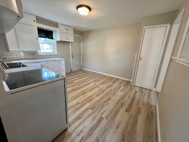 511 Division St N, Clara City, MN 56222 - kitchen with a sink, light wood finished floors, white cabinetry, tasteful backsplash, and range