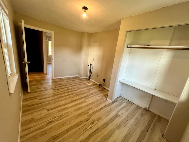 511 Division St N, Clara City, MN 56222 - unfurnished bedroom featuring baseboards, a closet, a textured ceiling, and wood finished floors