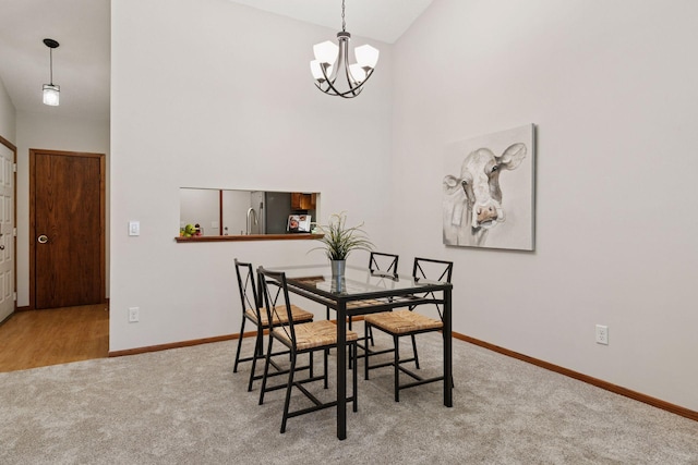 carpeted dining space with baseboards, a high ceiling, and a chandelier
