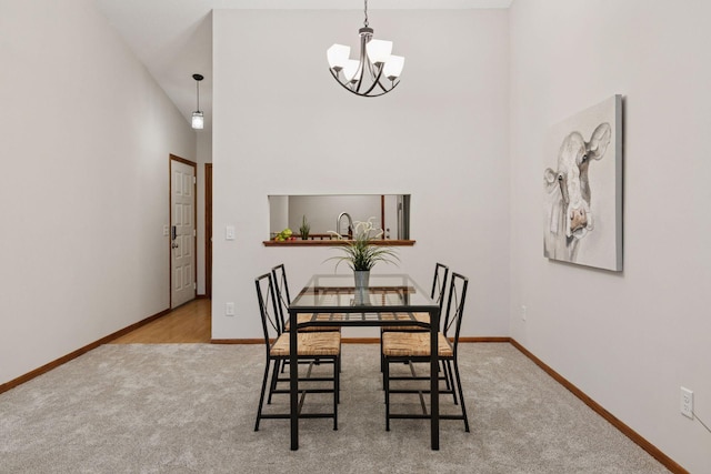 dining area featuring a towering ceiling, carpet flooring, a chandelier, and baseboards