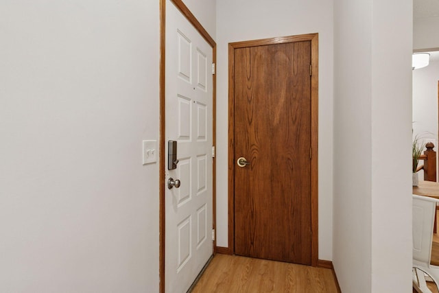 corridor with light wood finished floors and baseboards