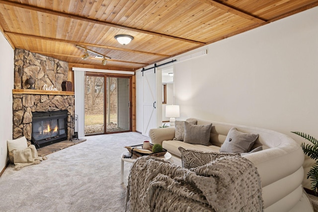 carpeted living room with a barn door, a stone fireplace, beam ceiling, and wooden ceiling