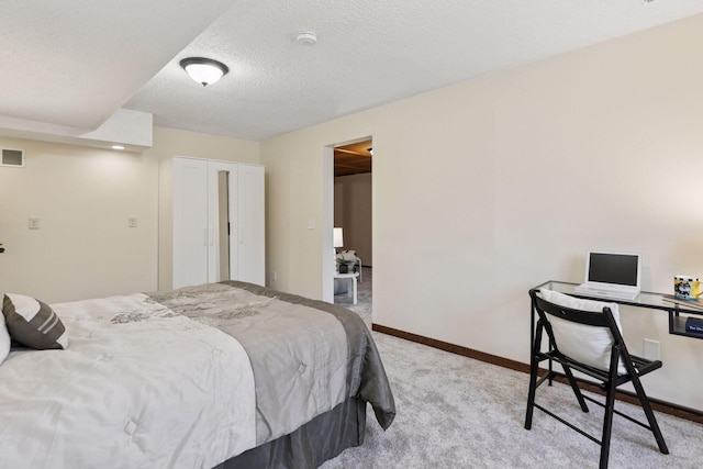 carpeted bedroom with baseboards, a textured ceiling, visible vents, and a closet