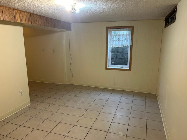 spare room featuring a textured ceiling, wood walls, and light tile patterned floors