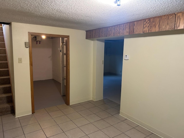 tiled empty room featuring a textured ceiling