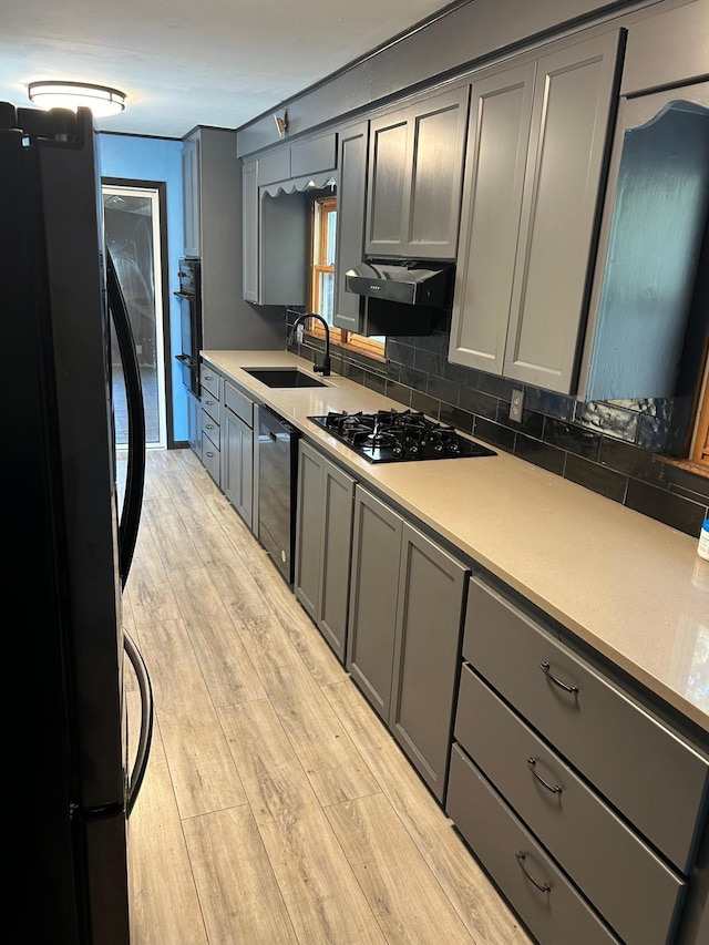 kitchen featuring sink, gray cabinetry, light hardwood / wood-style flooring, black appliances, and ventilation hood