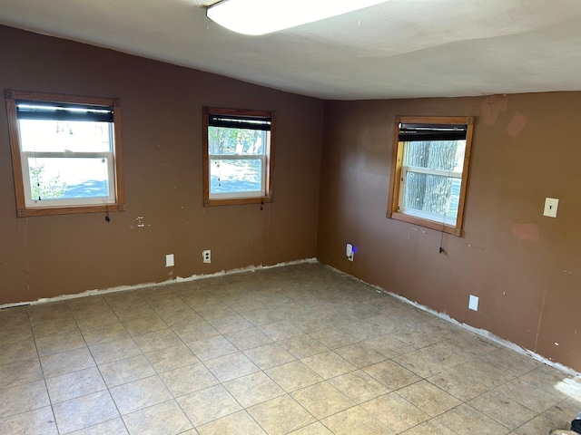 unfurnished room featuring lofted ceiling and a wealth of natural light