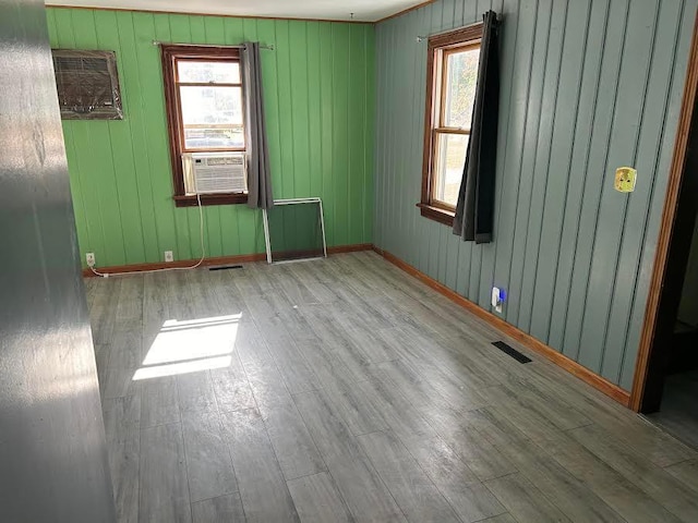 spare room with cooling unit, wooden walls, and light hardwood / wood-style flooring