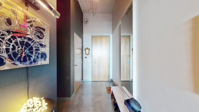 hallway with a towering ceiling and concrete floors