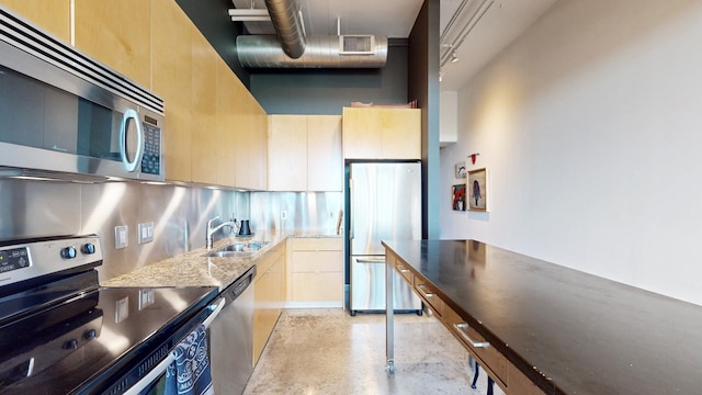 kitchen with light brown cabinetry, appliances with stainless steel finishes, sink, light stone counters, and decorative backsplash