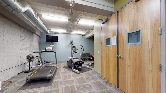 workout room with brick wall and carpet floors