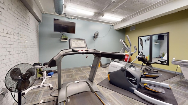 workout area featuring brick wall and carpet