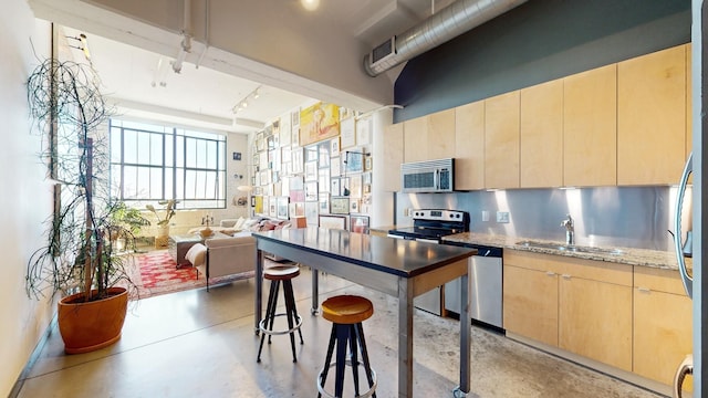 kitchen with tasteful backsplash, light stone countertops, sink, stainless steel appliances, and light brown cabinets