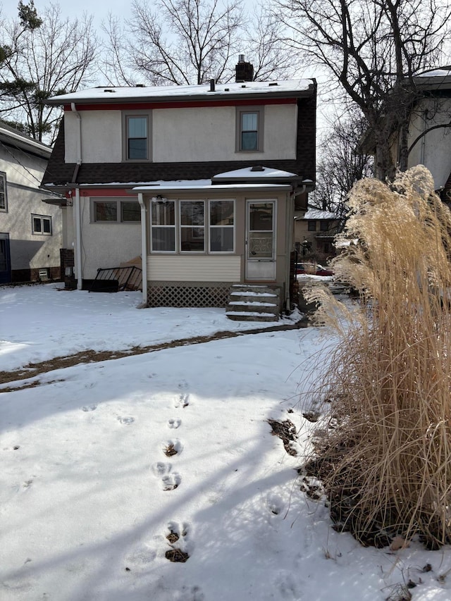 view of front of property with entry steps, a chimney, and stucco siding