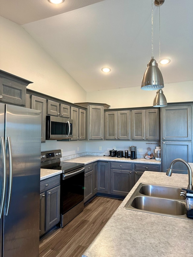 kitchen featuring vaulted ceiling, sink, pendant lighting, and stainless steel appliances