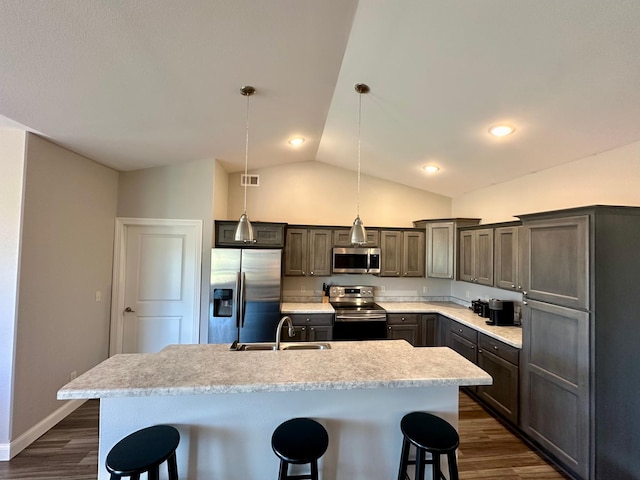 kitchen featuring hanging light fixtures, sink, a center island with sink, appliances with stainless steel finishes, and a breakfast bar