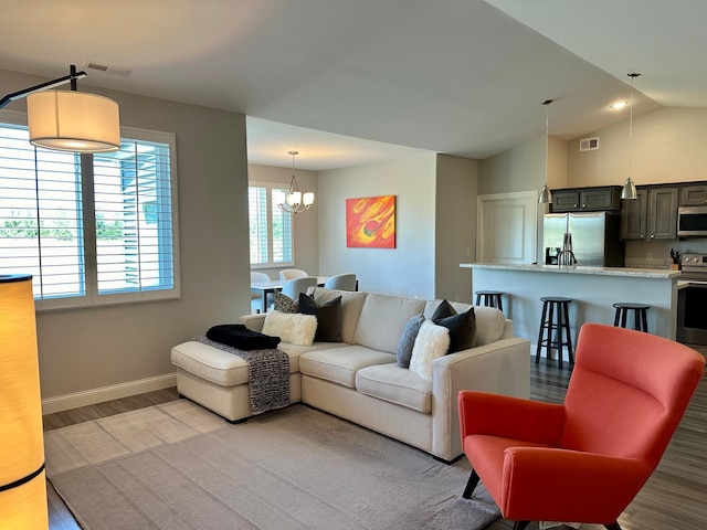 living room featuring light wood-type flooring, a chandelier, and vaulted ceiling