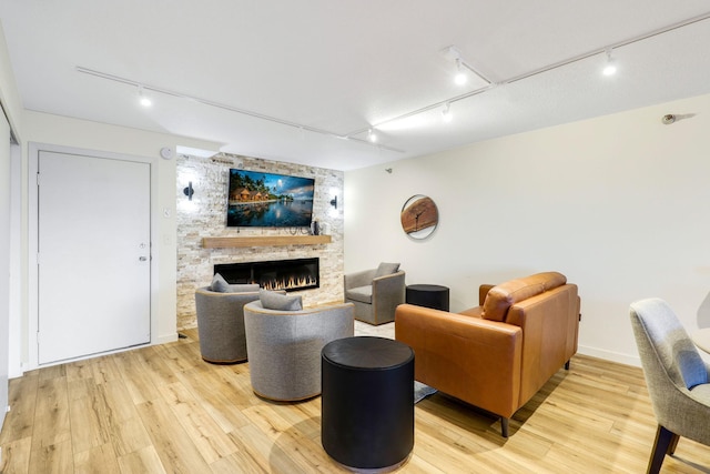 living room featuring a stone fireplace and light hardwood / wood-style flooring