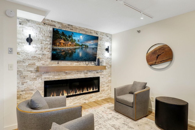 living room featuring a fireplace, hardwood / wood-style flooring, and track lighting