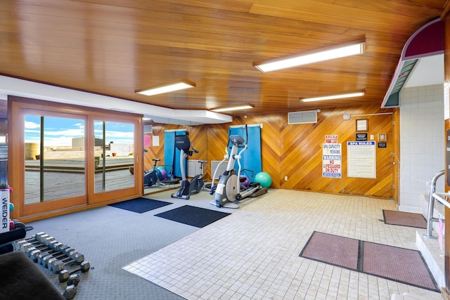 exercise room featuring wood ceiling, carpet floors, and wooden walls