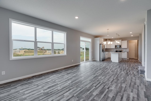 unfurnished living room featuring a textured ceiling, an inviting chandelier, and hardwood / wood-style flooring