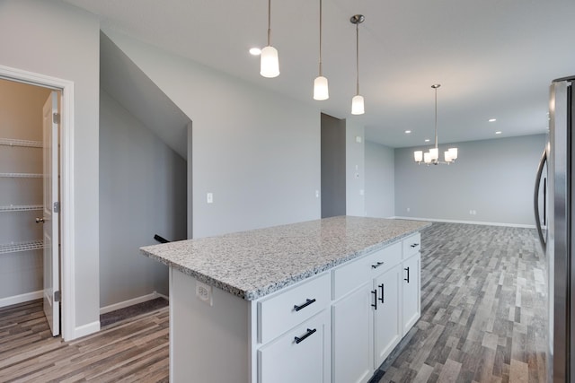 kitchen featuring a kitchen island, stainless steel fridge, white cabinetry, and hardwood / wood-style floors