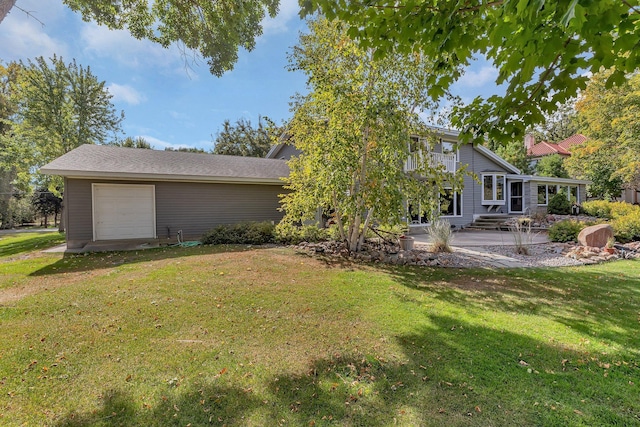 rear view of house with a garage, a patio area, and a lawn