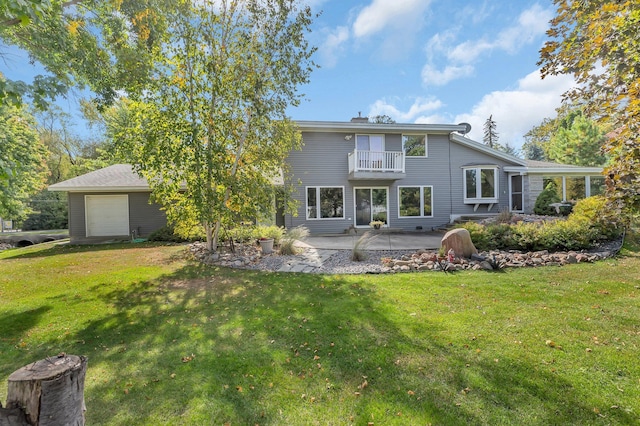 rear view of property featuring a balcony, a yard, a patio, and a garage