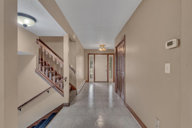 tiled entrance foyer with baseboard heating and a textured ceiling