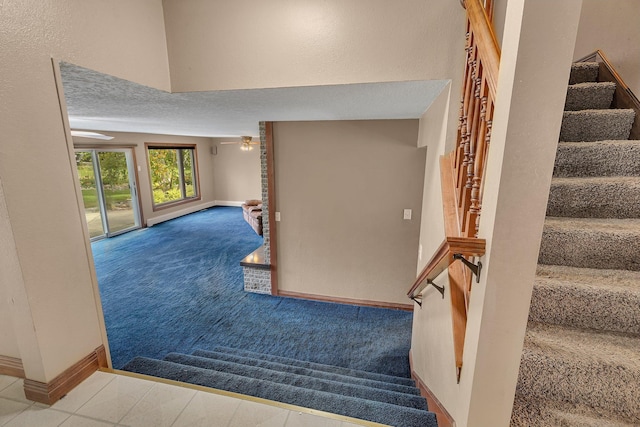 stairs featuring ceiling fan and carpet floors