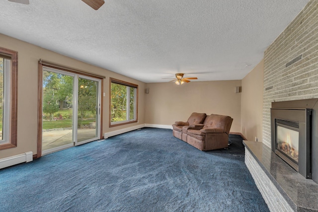 unfurnished living room featuring ceiling fan, a fireplace, a textured ceiling, and dark colored carpet