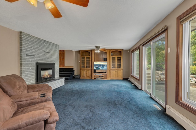 carpeted living room featuring ceiling fan, a healthy amount of sunlight, a brick fireplace, and a baseboard heating unit