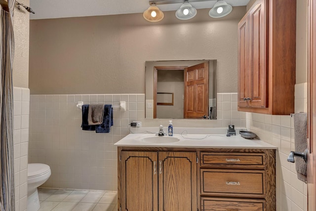 bathroom with tile patterned flooring, vanity, tile walls, and toilet