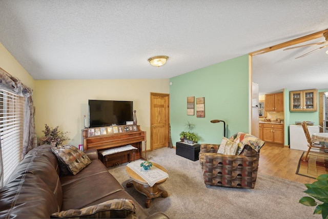 living room with ceiling fan, a textured ceiling, light hardwood / wood-style flooring, and vaulted ceiling