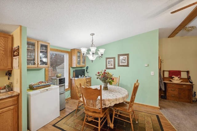 dining room featuring light wood-type flooring, a notable chandelier, and a textured ceiling