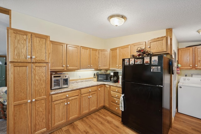 kitchen featuring black appliances, washer / clothes dryer, light wood-type flooring, and a textured ceiling