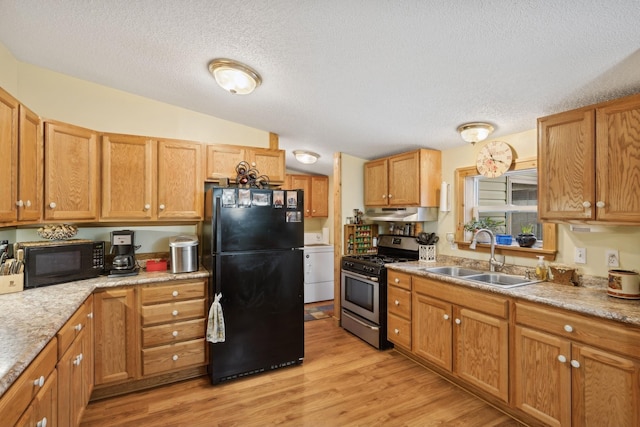 kitchen featuring a textured ceiling, black appliances, washer / dryer, light hardwood / wood-style floors, and sink