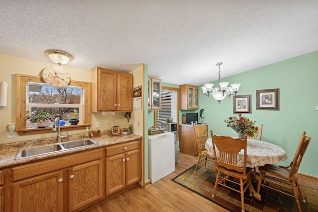 kitchen featuring a textured ceiling, light hardwood / wood-style floors, sink, hanging light fixtures, and a notable chandelier