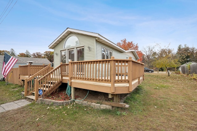 back of house with a wooden deck and a lawn