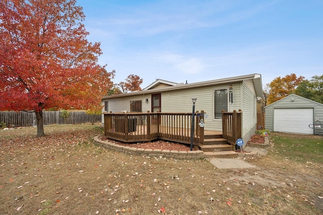 rear view of property featuring a garage, a deck, and an outbuilding