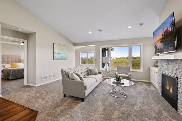 living room featuring carpet floors, a fireplace, lofted ceiling, and ceiling fan